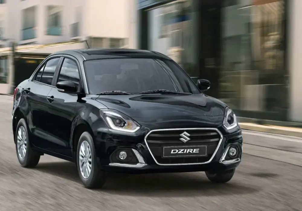 Auto sedán Suzuki Dzire negro conduciendo por una calle de la ciudad.