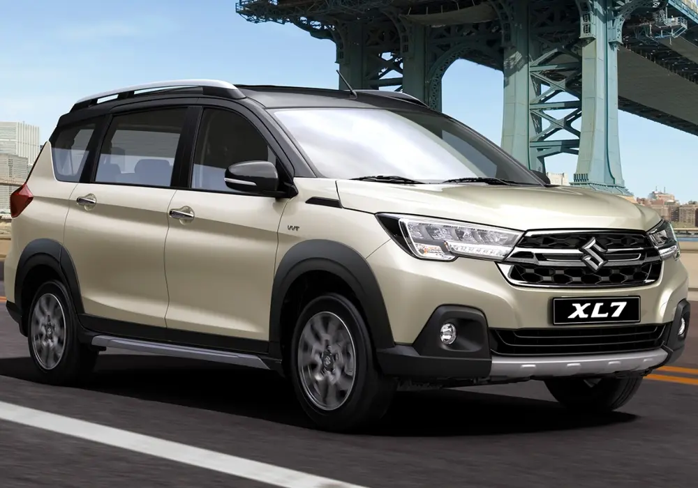 Suzuki XL7 dorado claro conduciendo por una carretera con un puente