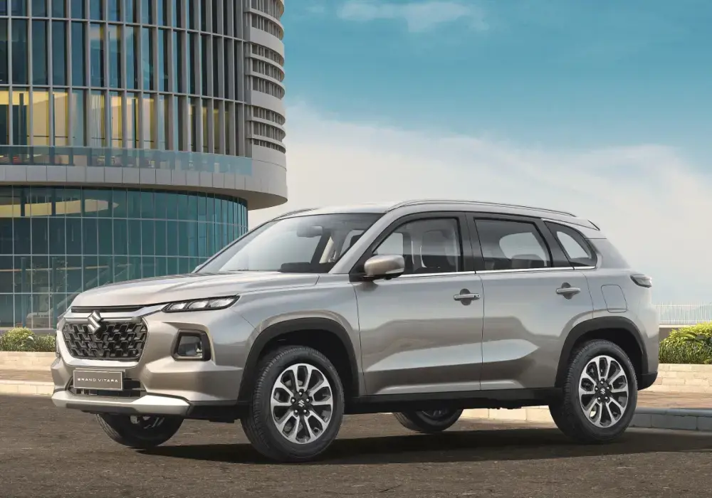 Suzuki Grand Vitara color gris plata estacionado frente a un edificio moderno.